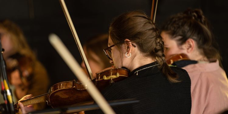 Photo of female student from the back playing the violin 