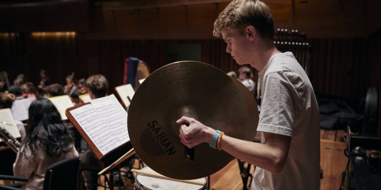 Junior student playing cymbals on stage 