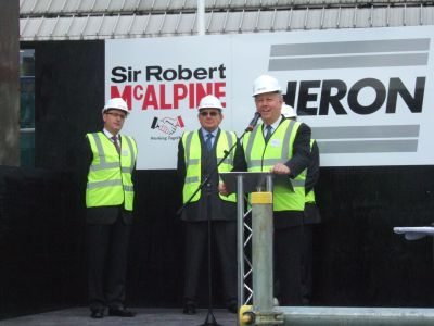 Barry Ife stood in front Sir Robert McAlpine and Heron sign outside Milton Court construction