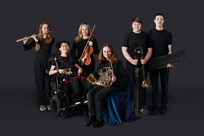 National Open Youth Orchestra musicians holding instruments in front of black background