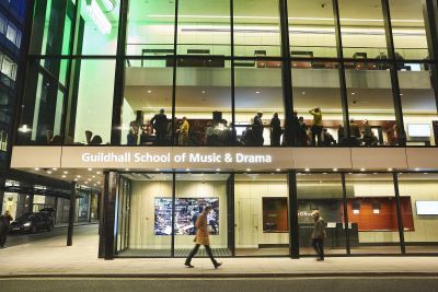 Passers by walking past Milton Court at night