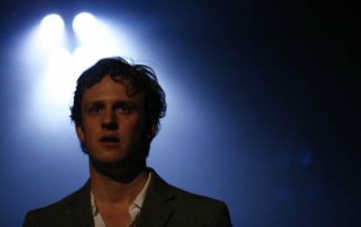 Richard Goulding on stage, with stage lights behind him